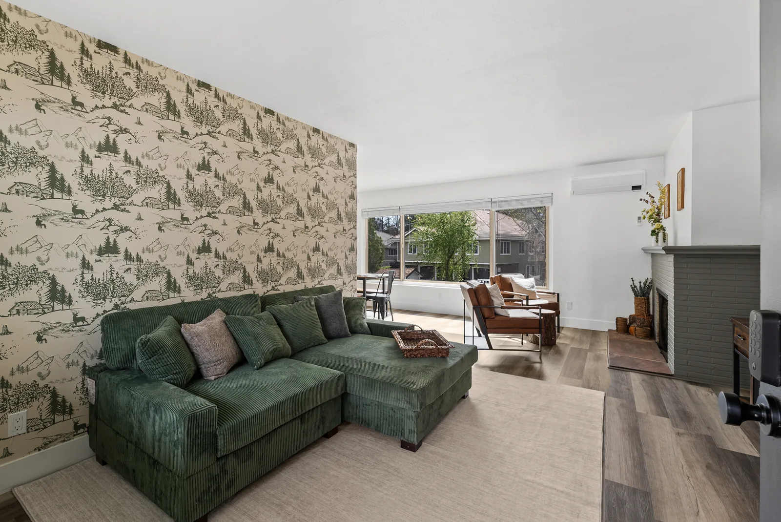 Glenmanor living room after: green mountain-toile feature wall, green sectional and styled lounge
