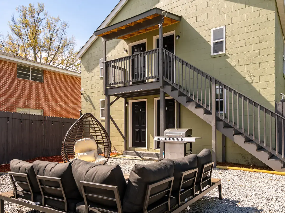House St after: rebuilt staircase and balcony, gravel courtyard with outdoor lounge, grill and string lights