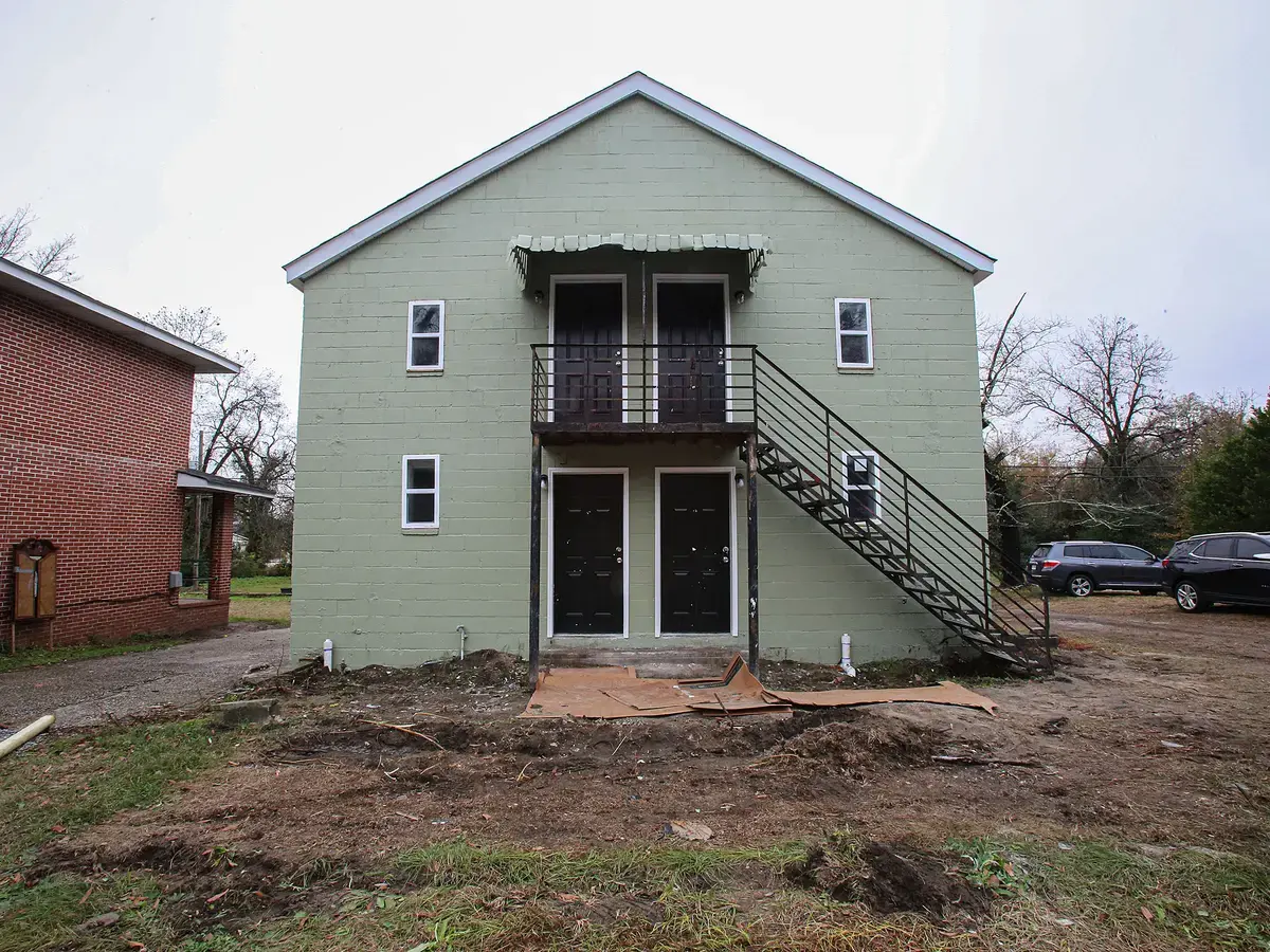 House St before: abandoned 4-plex with rusted steel stairs and bare dirt yard