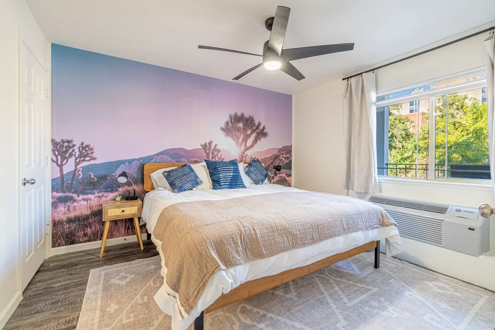 Midtown Manor Unit 1 after: furnished bedroom with desert mural feature wall, styled bed and decor