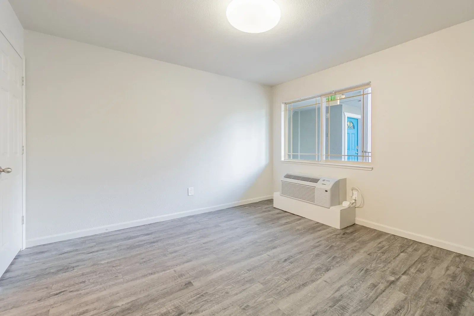Midtown Manor Unit 1 before: empty room with bare walls and wall AC unit