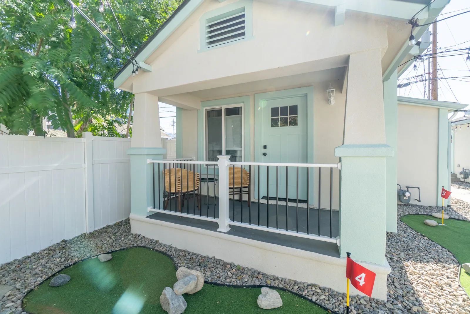 Vine St cottage after: refreshed stucco exterior, white porch railing, putting green