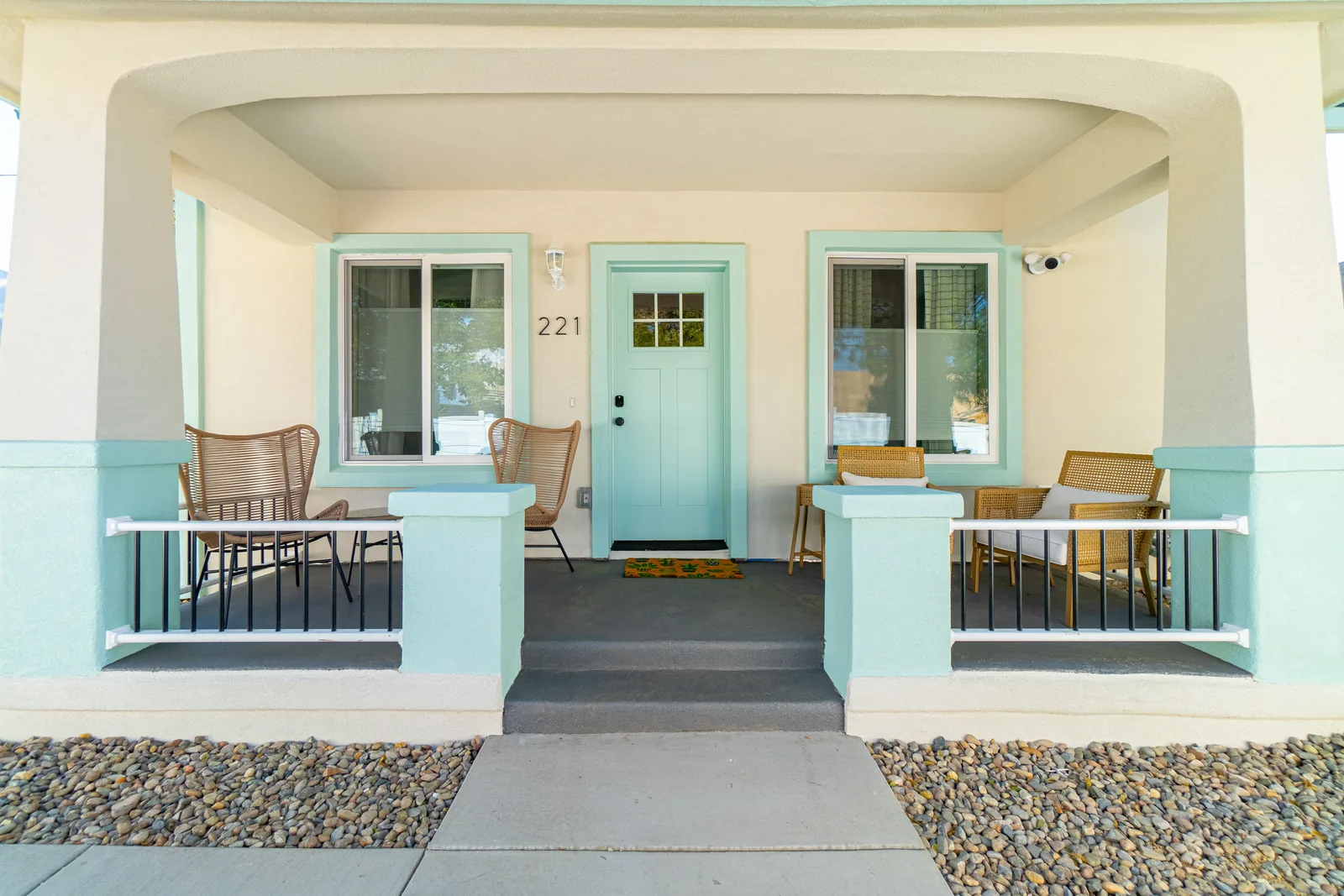 Vine St front porch after: clean stucco facade with teal craftsman door, number 221, woven chairs